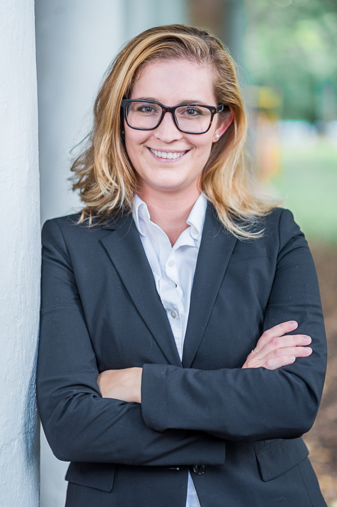 Woman smiles with arms crossed in a professional-headshot style photo