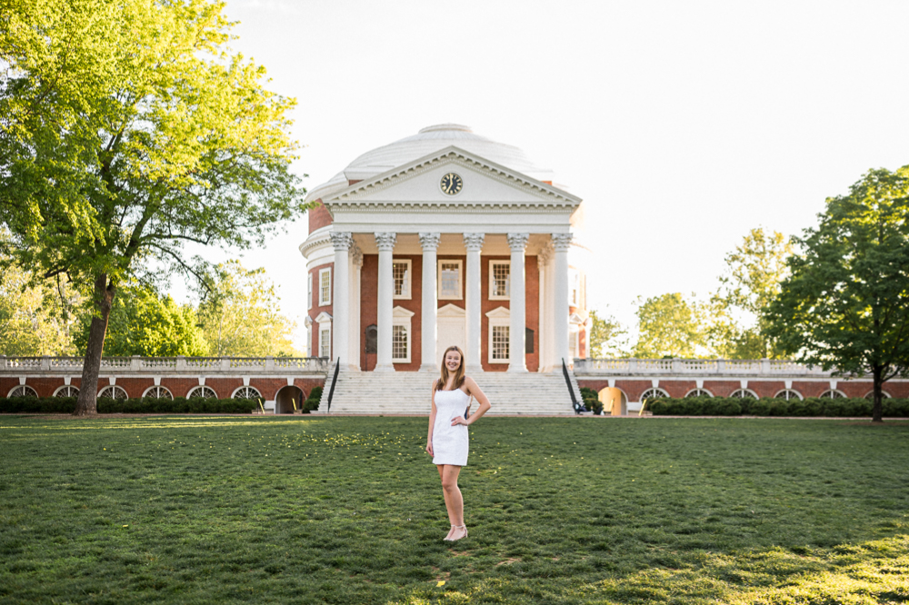 A college senior poses for her UVA grad photoshoot. She's standing on the Lawn with the Rotunda behind her -- the Lawn is completely empty as the sun rises behind her.