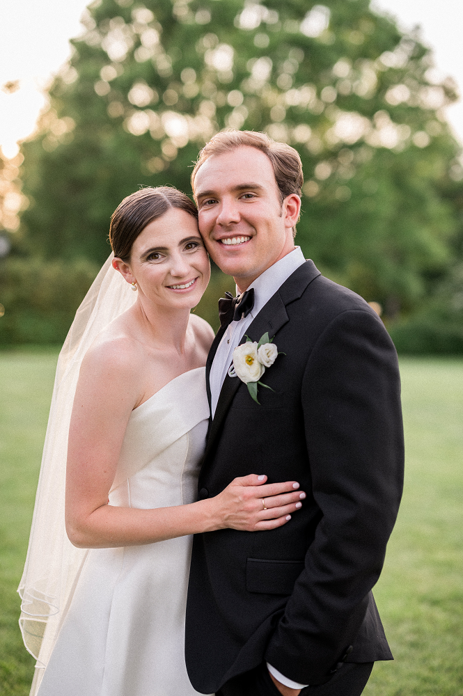 A couple smiles and looks at the camera during golden hour at their Farmington Country Club wedding, captured beautifully by Hunter and Sarah Photography