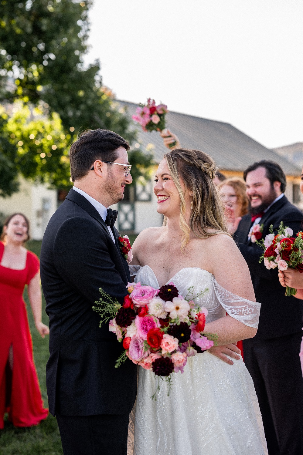 A husband and wife smile as they look into each other's eyes on their wedding day. They're surrounded by their cheering wedding party at King Family Vineyards, captured by Hunter and Sarah Photography.