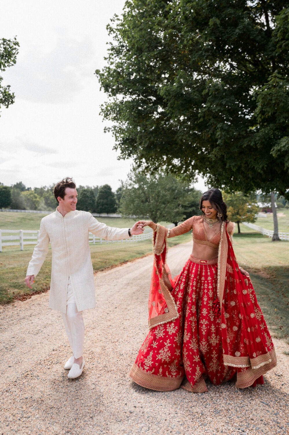 An Indian Bride and her Jewish groom walk up the driveway at Castle Hill Cider in traditional Indian wedding attire on their wedding day. This Indian-Jewish Fusion Wedding was beautifully captured by Hunter and Sarah Photography.