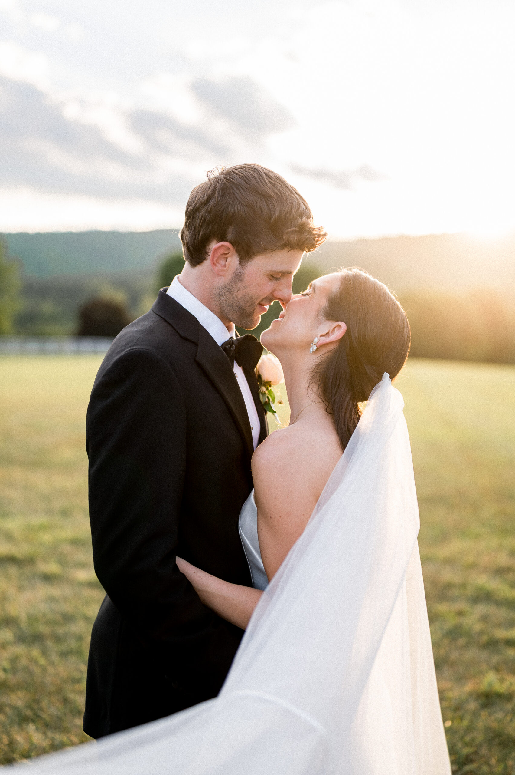A beautiful young couple klisses at sunset, dressed sharply in their wedding attire. This timeliess castle hill wedding photo was captured by Hunter and Sarah Photography