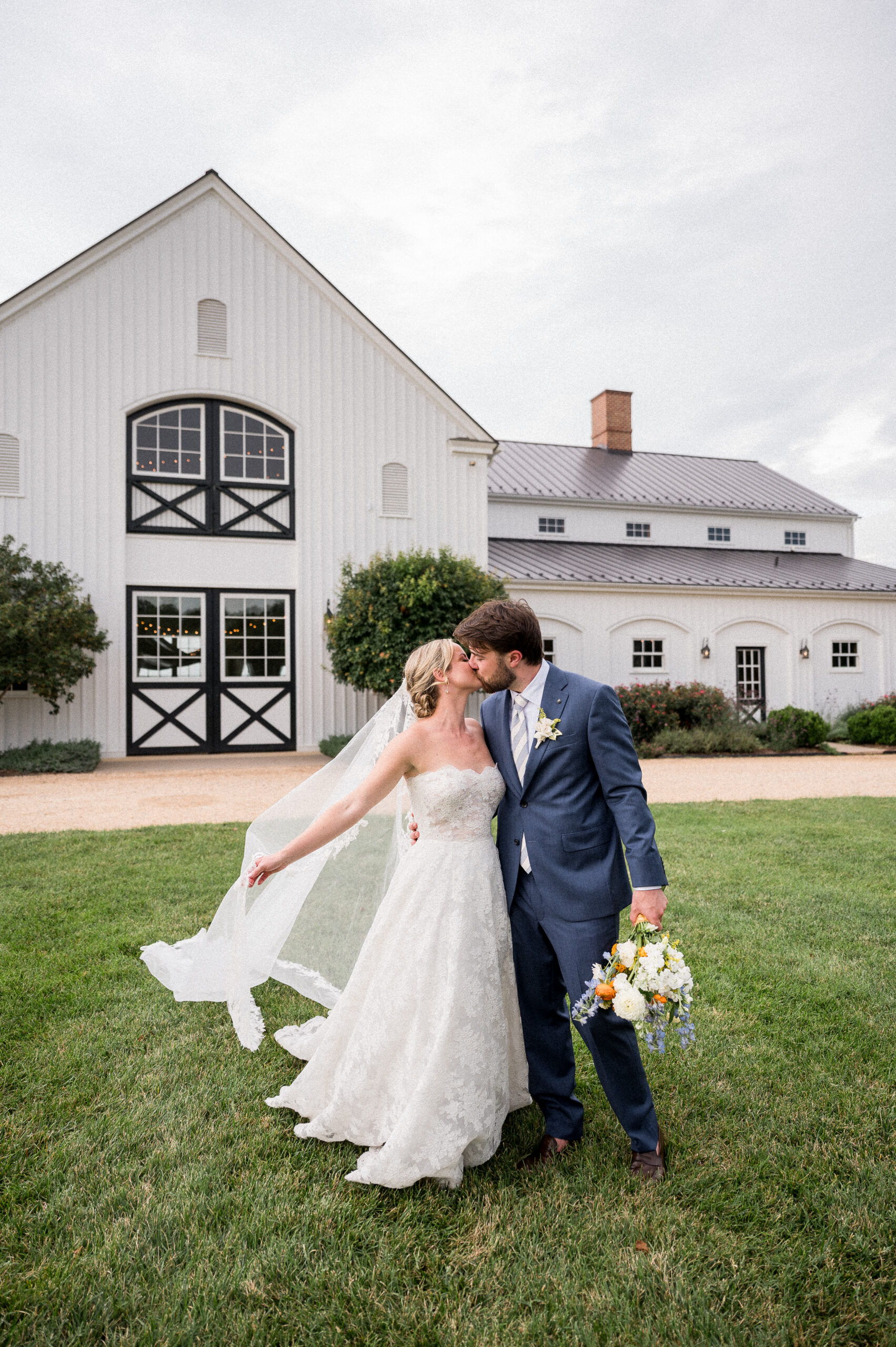 A bride and groom pose in front of Castle Hill Cider during their coastal-inspired wedding, captured by Hunter and Sarah Photography